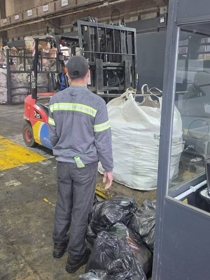 Entrega dos resíduos do cartório na unidade da CICLO, com um funcionário de costas diante de uma empilhadeira e de sacos de material